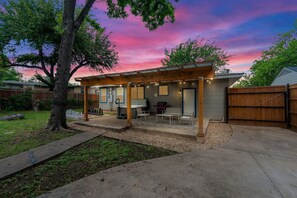 A covered patio with a grill, seating, and a view of the backyard. - Rare Exclusive Retreat Private Hot Tub King Bed (Arlington)