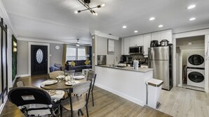 A modern kitchen with stainless steel appliances, a dining area with a table set for four, and a visible laundry machine. - Rare Exclusive Retreat Private Hot Tub King Bed (Arlington)