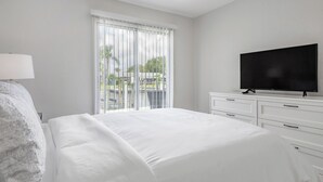 Ein Hotelzimmer mit einem großen Bett, einem Fernseher auf einer Kommode und Blick ins Freie durch das Fenster.