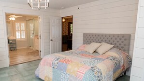 A bedroom with a large bed, a chandelier, and a view of a bathroom and dining area. - 371 Mountain Hill Rd, Fortson (Hamilton)