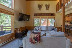 A cozy living room with a sofa, a TV mounted on the wall, and a sign that reads 'THE PLACE'. - Alpine Breakwater (Alpine)