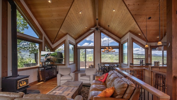 A spacious living room with a high ceiling, large windows, a fireplace, leather sofas, and a dining area. - Alpine Recharge (Alpine)