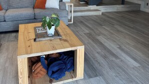 Ett modernt vardagsrum med ett träbord, en grå soffa och en trappa i bakgrunden.