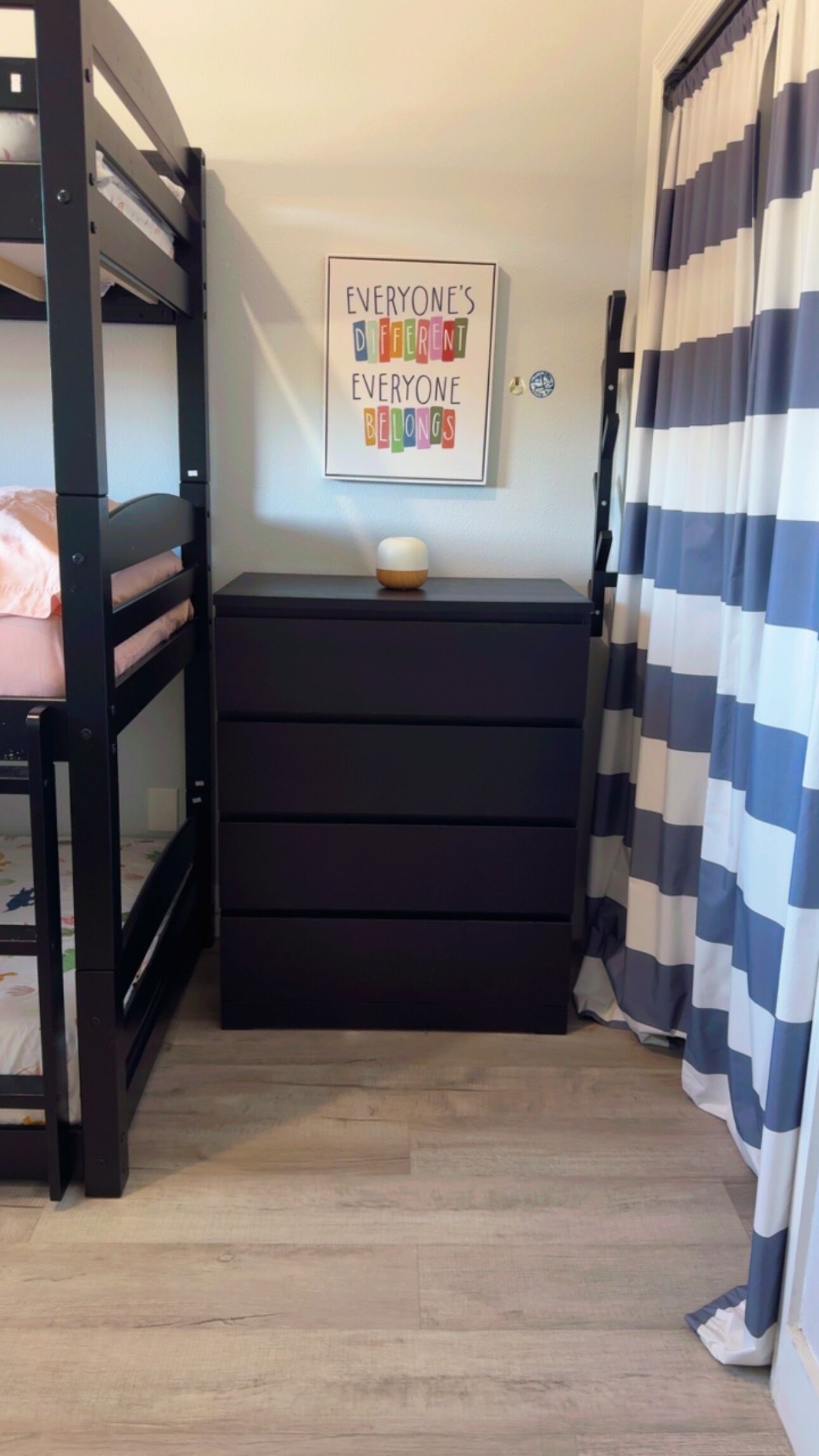 A bunk bed with a black dresser and a motivational poster.