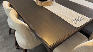 En matplats med ett långt träbord, bekväma stolar, en flätad korg med ett kort i och en orkidé i en kruka.