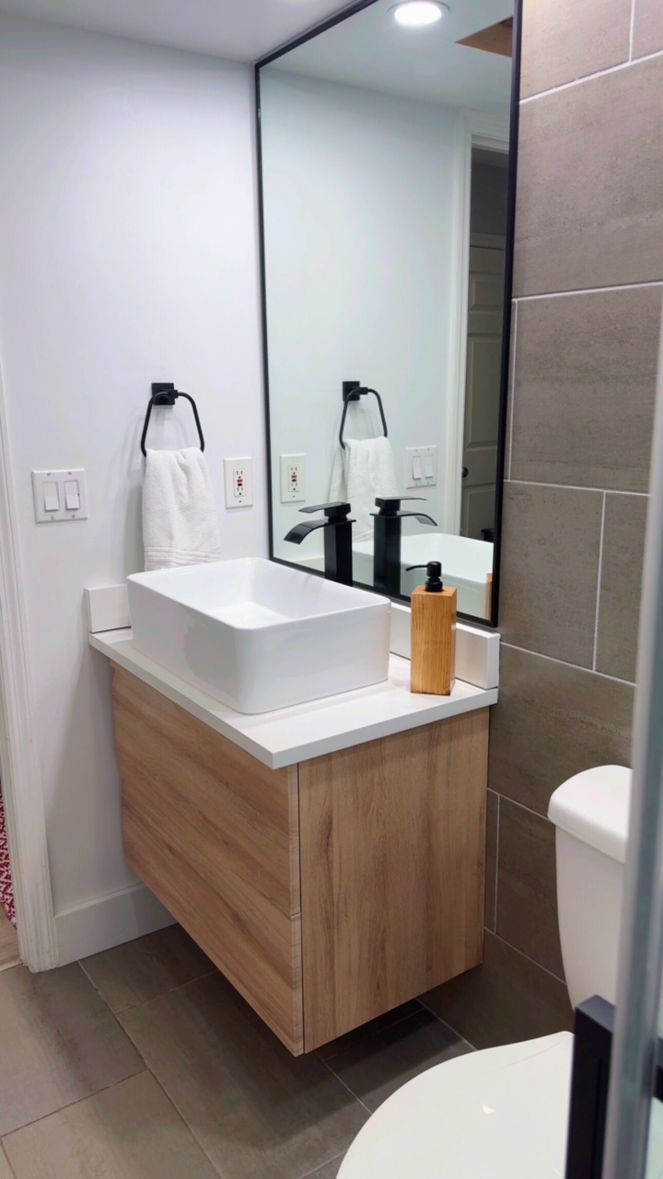 Un baño moderno con un tocador blanco, un espejo grande y un inodoro.