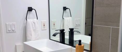 Un baño moderno con un tocador blanco, un espejo grande y un inodoro.