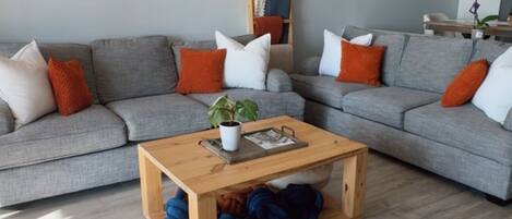 Un salon moderne avec un canapé gris, une table basse en bois et une petite plante.