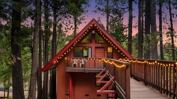 Una baita con facciata rossa, un balcone con luci decorative e un pontile in legno.