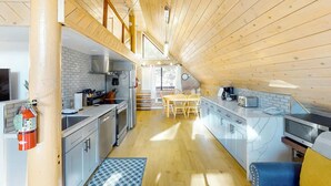 Una cucina compatta con elettrodomestici moderni, un'area pranzo con tavolo e sedie e un estintore a vista.