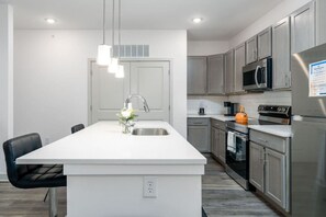 A modern kitchen with a central island, stainless steel appliances, and a pendant light. - Affordable Getaway Whitestown (Whitestown)