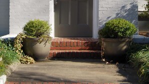 A white brick building with a grey door, two wall-mounted lanterns, and a sign reading '71 Standish Avenue.' - Standish House by BCA Furnished Apartments Standish House (Atlanta)