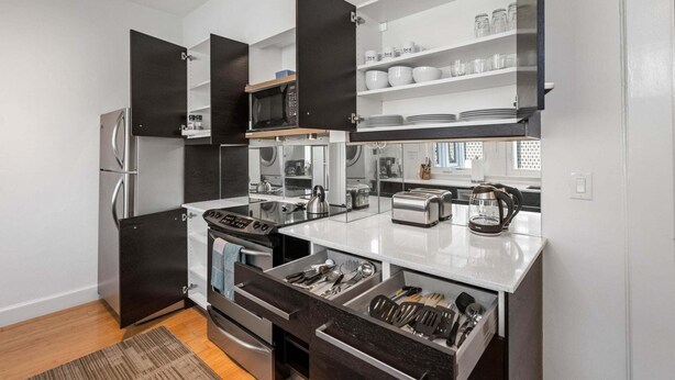 A modern kitchen with a built-in microwave, toaster, and kettle, along with a refrigerator and oven. - Standish House by BCA Furnished Apartments Standish House (Atlanta)