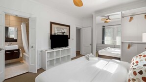 A hotel room with a bed, a TV, a bathroom with a shower, and a ceiling fan. - Standish House by BCA Furnished Apartments Standish House (Atlanta)