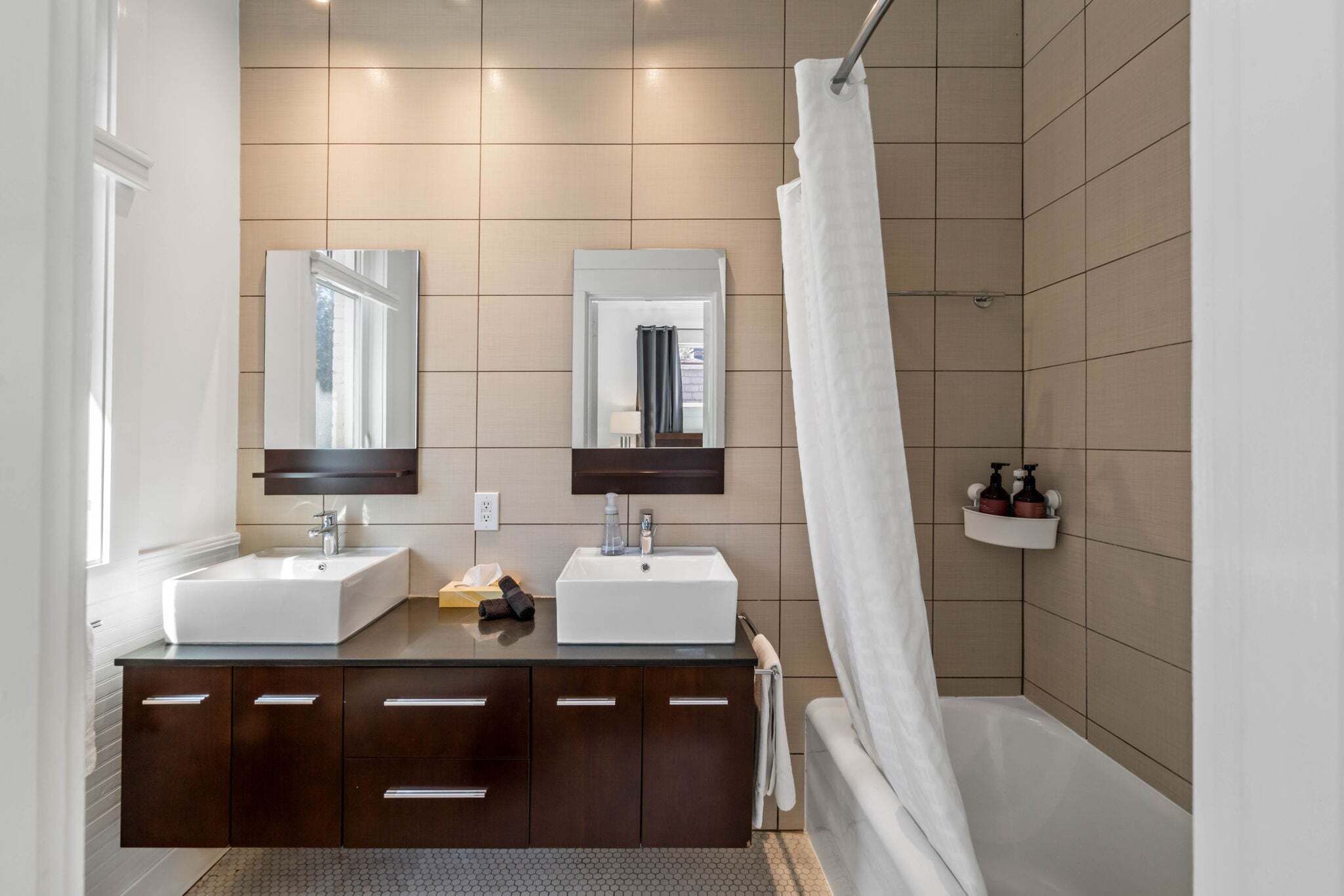A modern bathroom with two sinks, a shower, and a towel rack.