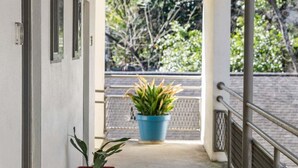 A covered outdoor corridor with a concrete floor, metal railing, and potted plants. - Studios On 25th by BCA Furnished Apartments Studio 05 E (Atlanta)