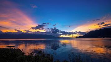 A calm lake at sunset with mountains in the background.