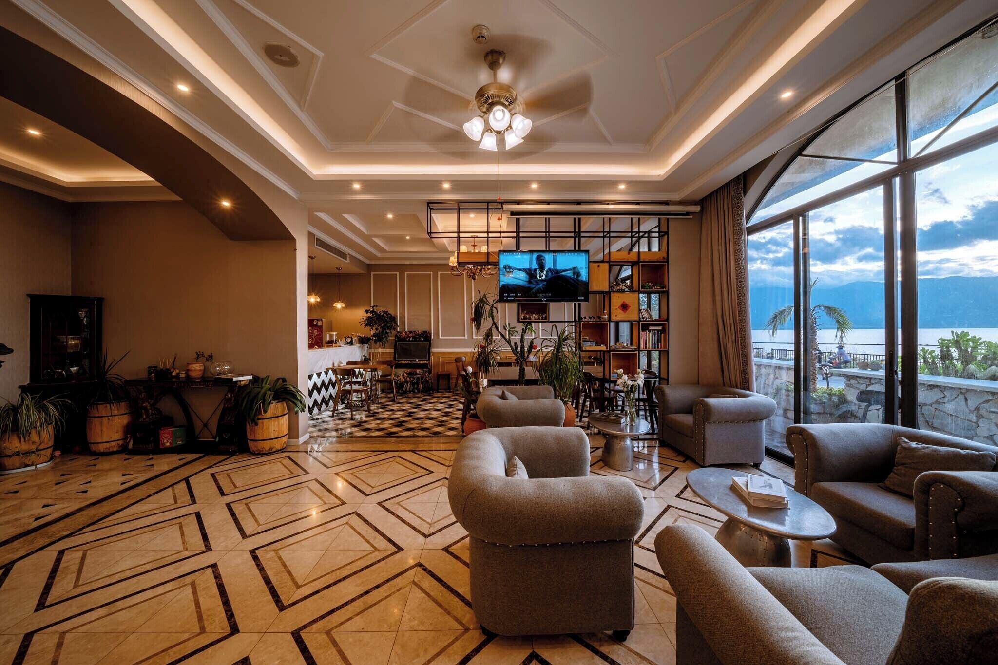A spacious lobby with a checkered floor, comfortable seating, a television, and a view of the sea.