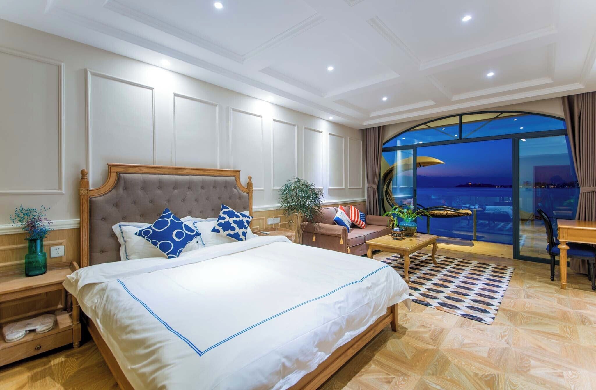 A spacious bedroom with a large bed, a view of the sea, and a balcony with a table and chairs.