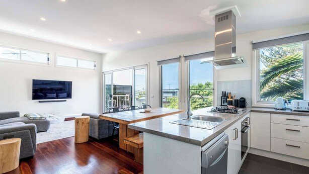 Een moderne keuken met een centraal eiland, grote ramen en een eetgedeelte met uitzicht.