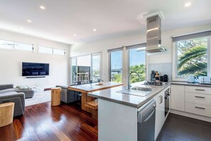 A modern kitchen with a central island, large windows, and a dining area with a view. - Central Torquay House , 300m to beach (Torquay)