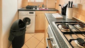 Une cuisine de taille réduite équipée d’un lave-linge, d’une cuisinière et d’un évier.