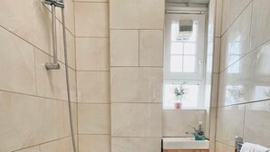 Une salle de bain avec une baignoire, un lavabo et une fenêtre.