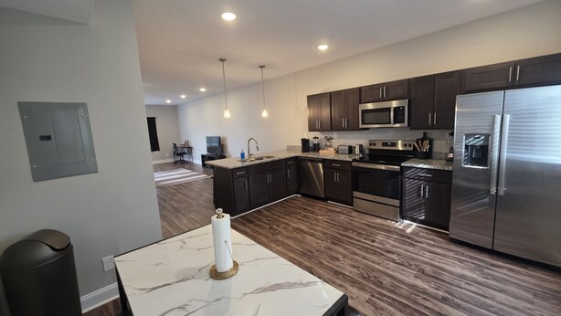 A modern kitchen with dark wood cabinets, stainless steel appliances, and a marble countertop. - Legacy Executive Retreat (Clarksville)