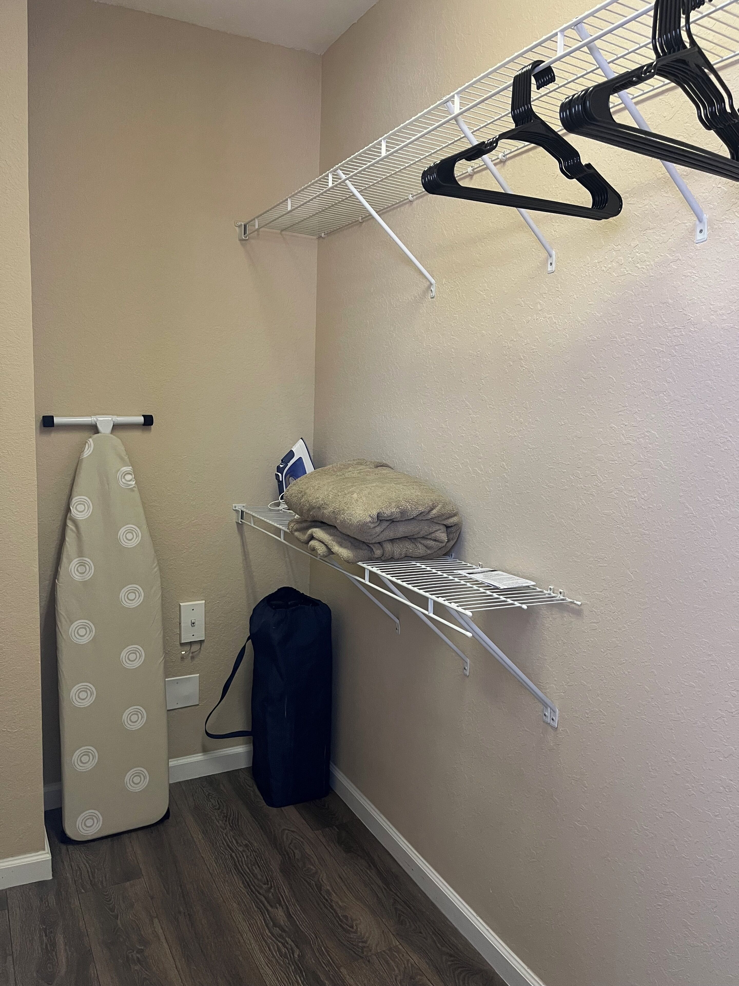 A laundry area with a hanging rack, a shelf with folded towels, and a drying rack.