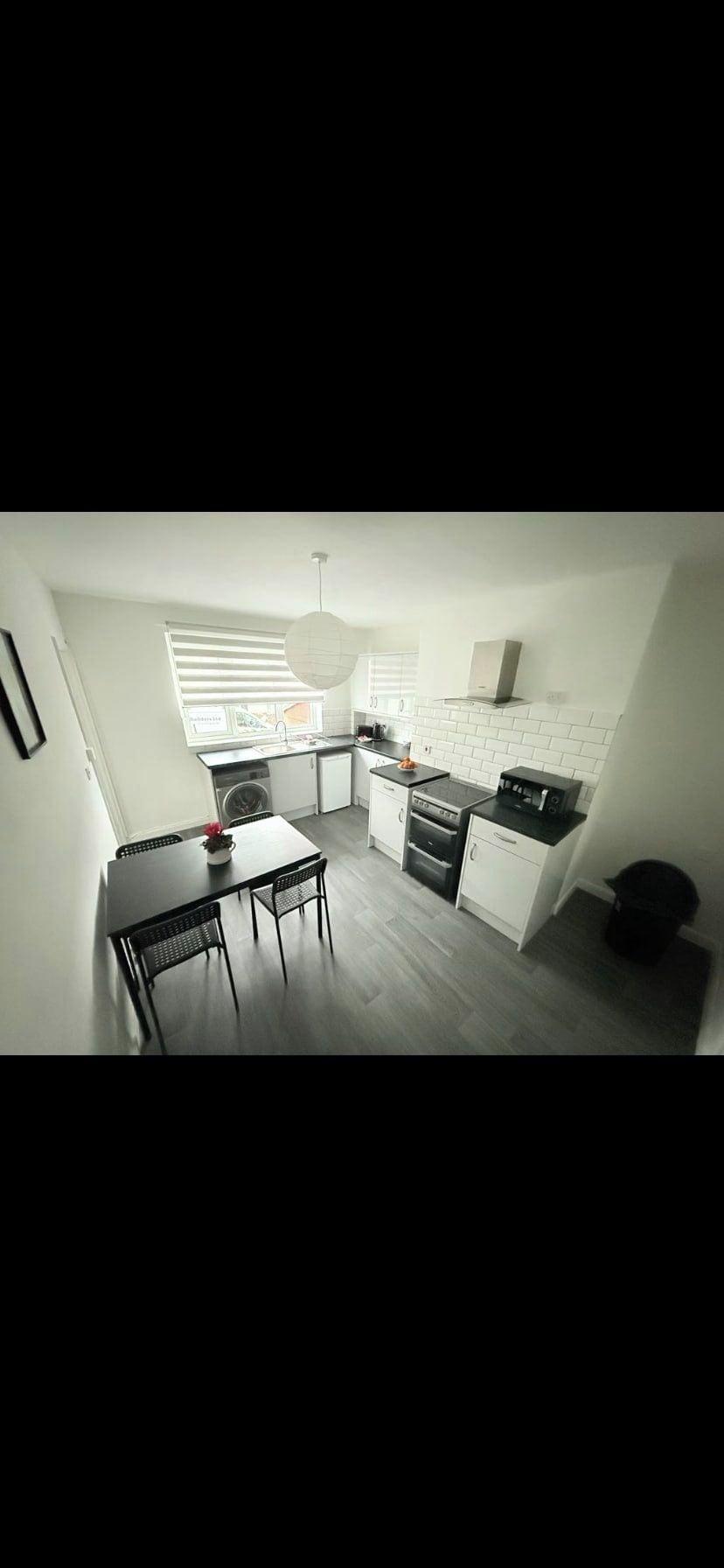 A compact kitchen with a dining area, a washing machine, and a built-in oven.