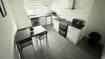 A compact kitchen with a dining area, a washing machine, and a built-in oven.