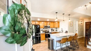 A modern kitchen with wooden cabinets, stainless steel appliances, and a central island with bar stools. - 193 Range (Breckenridge)
