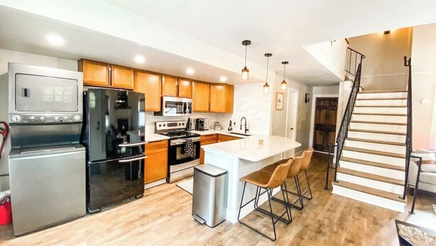 A modern kitchen with wooden cabinets, stainless steel appliances, and a central island with bar stools. - 193 Range (Breckenridge)