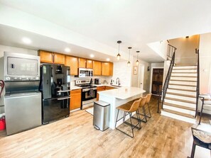 A modern kitchen with wooden cabinets, stainless steel appliances, and a central island with bar stools. - 193 Range (Breckenridge)