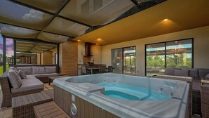 Un espacio exterior moderno con jacuzzi, asientos y un porche cubierto.