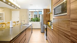 Una cocina moderna con una isla central, electrodomésticos de acero inoxidable, armarios de madera y un amplio ventanal con vistas al exterior.