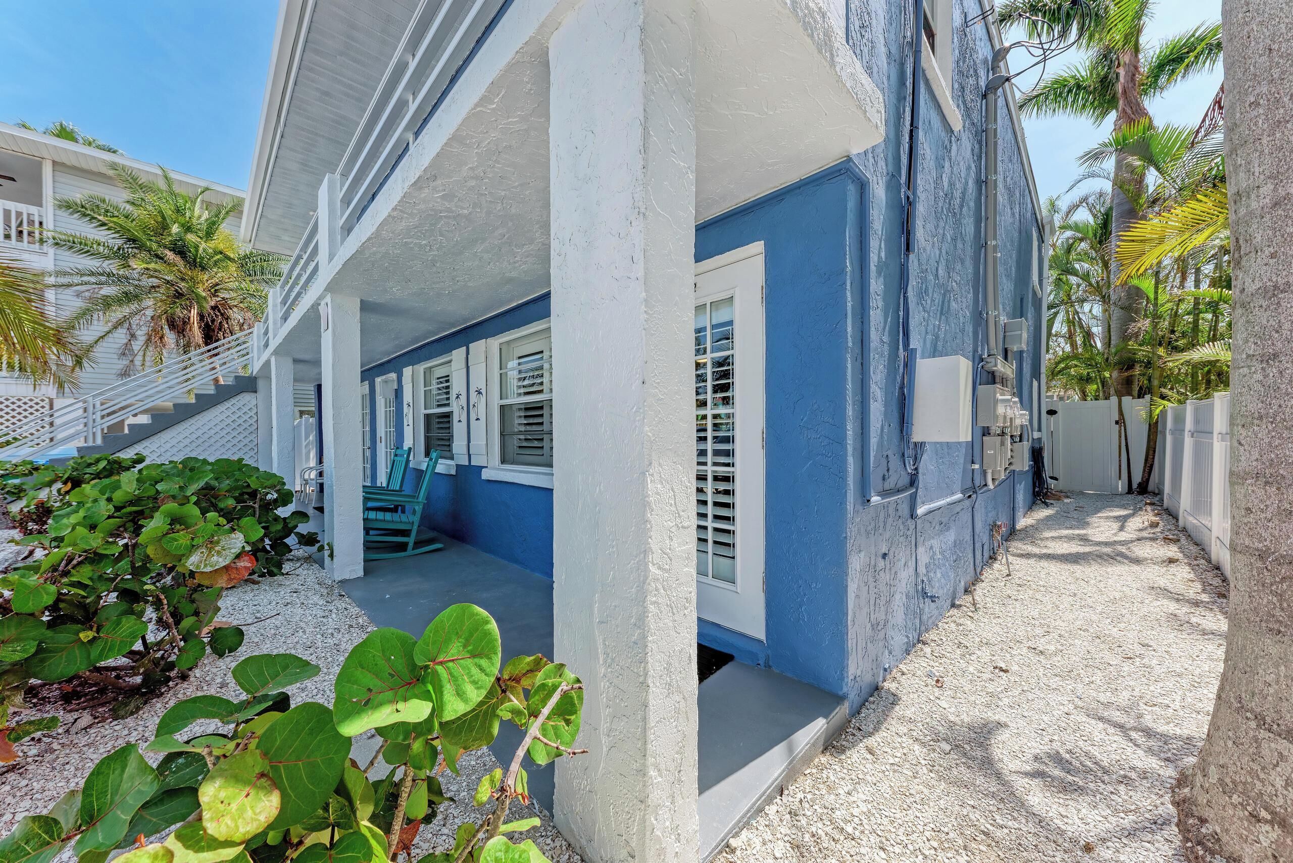 A beachfront property with a covered porch, white railings, and a blue exterior.