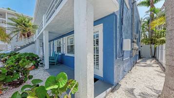 A beachfront property with a covered porch, white railings, and a blue exterior.