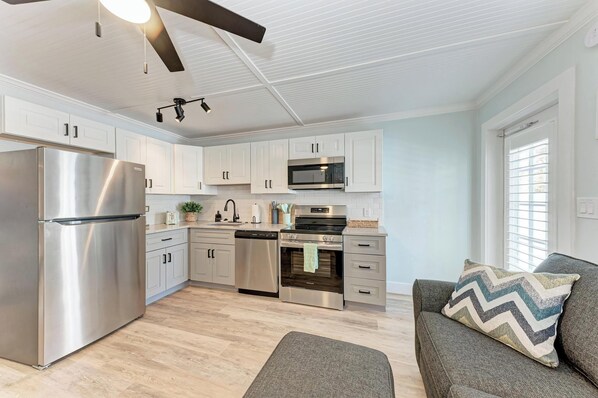 A modern kitchen with stainless steel appliances, white cabinetry, and a ceiling fan.
