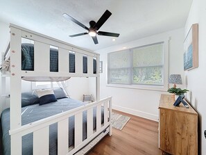 A bunk bed with a ceiling fan, a window with blinds, a wooden nightstand, and a plant. - 3716 7th Ave W (Bradenton)