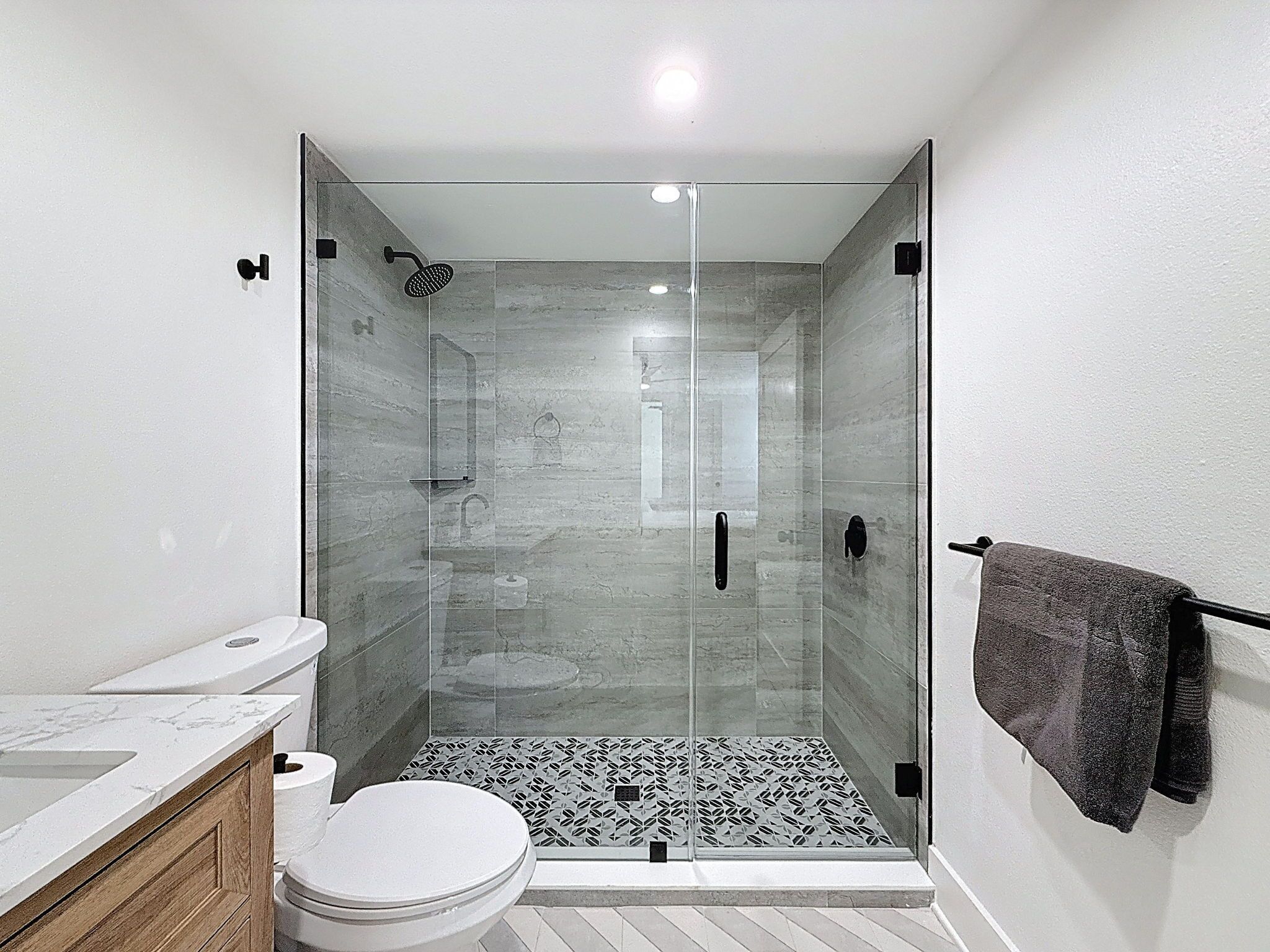 A modern bathroom with a glass-enclosed shower, a toilet, and a sink.