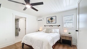 A bedroom with a bed, a ceiling fan, a nightstand, an air conditioning unit, and a window with blinds. - 3716 7th Ave W (Bradenton)