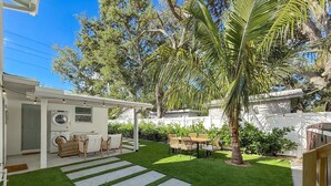 A backyard with a patio, outdoor seating, a palm tree, and a white building with a washing machine. - 3716 7th Ave W (Bradenton)