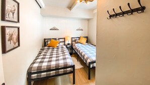 Una stanza con due letti, un soffitto in legno e un appendiabiti a muro.