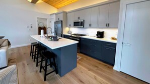 A modern kitchen with a central island, stainless steel appliances, and a wooden ceiling. - 1B Birch House (Bethlehem)