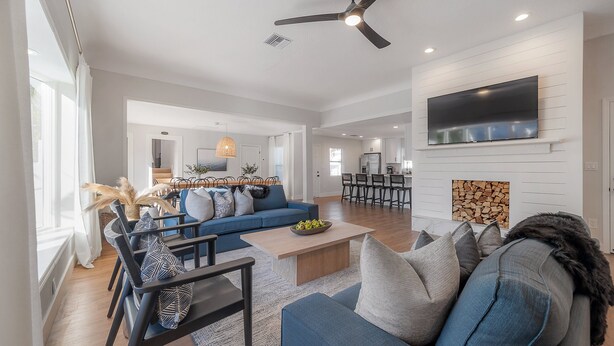 A spacious living room with a blue sofa, a coffee table, and a TV mounted on the wall. - 125 Harbor Bluff Dr (Largo)