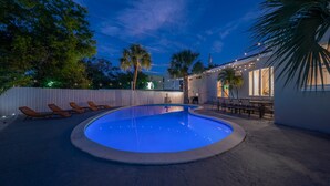 A swimming pool with lounge chairs, a patio area with tables and chairs, and a white fence. - 125 Harbor Bluff Dr (Largo)