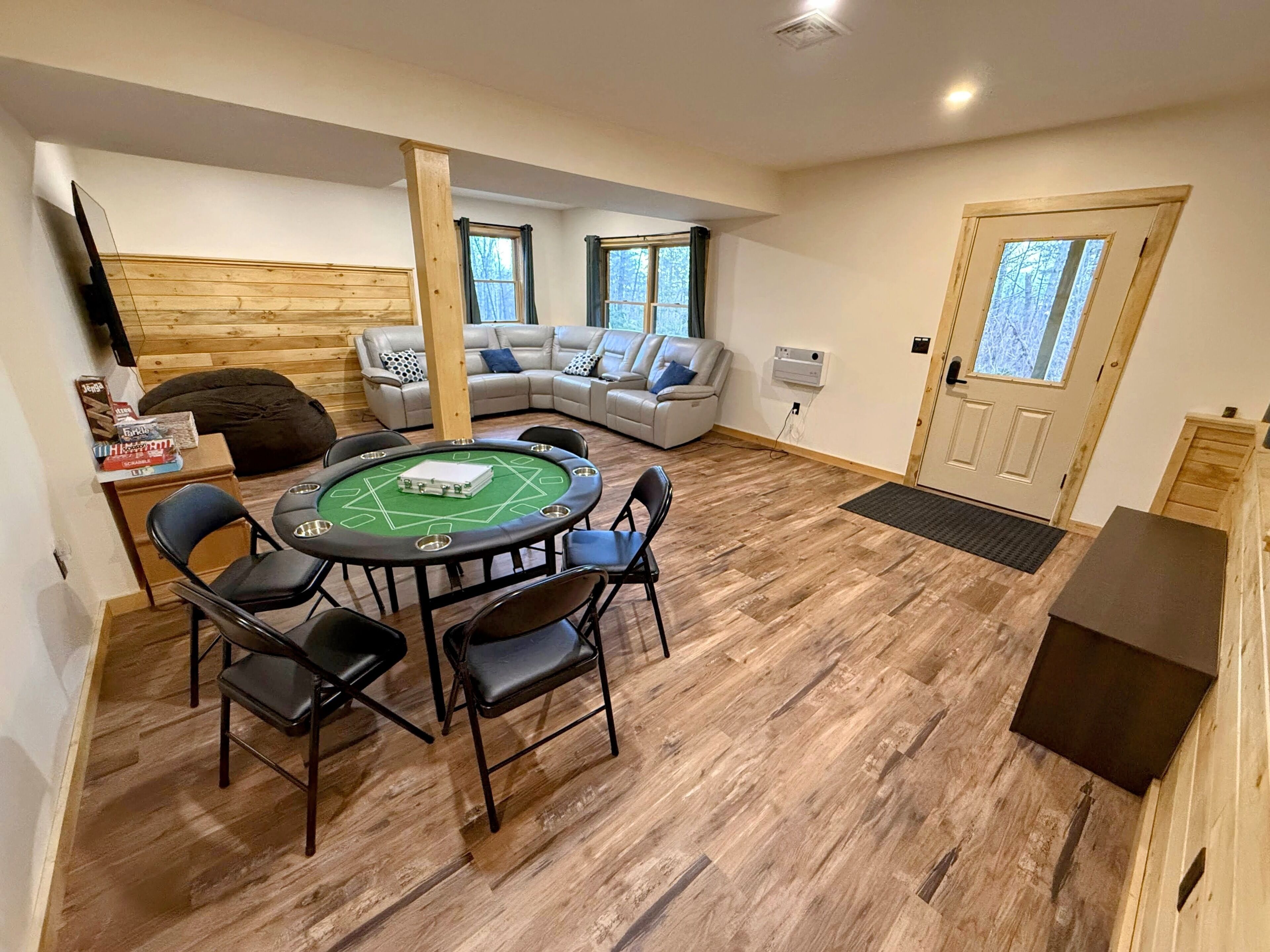 Una habitación acogedora con suelo de madera, una mesa redonda con sillas, un sofá y una puerta con ventanas.