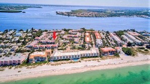 An aerial view of a coastal resort with multiple buildings, a beach, and a marina. - Runaway Bay (Bradenton Beach)