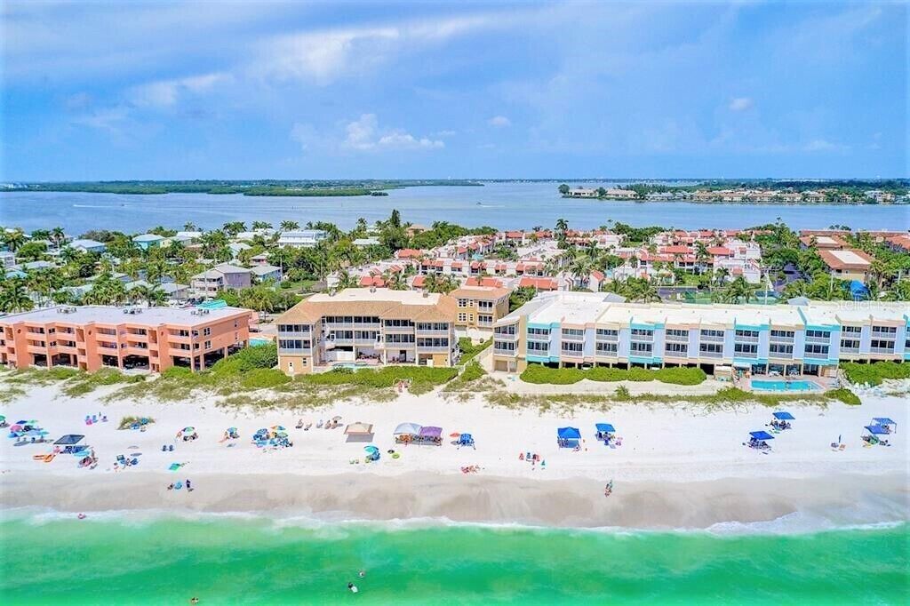 A coastal resort with beachfront villas, a pool, and a sandy beach.